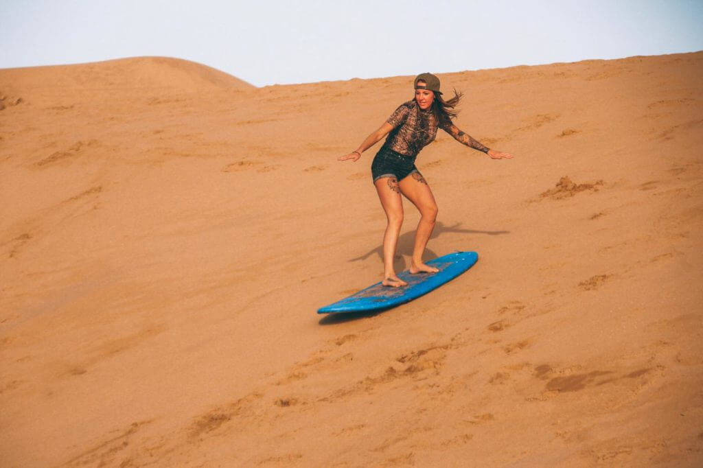 Surf girl in Morocco, sandboarding during a surf holiday to Morocco with the surfcamp in Taghazout Surf Paradise Morocco.