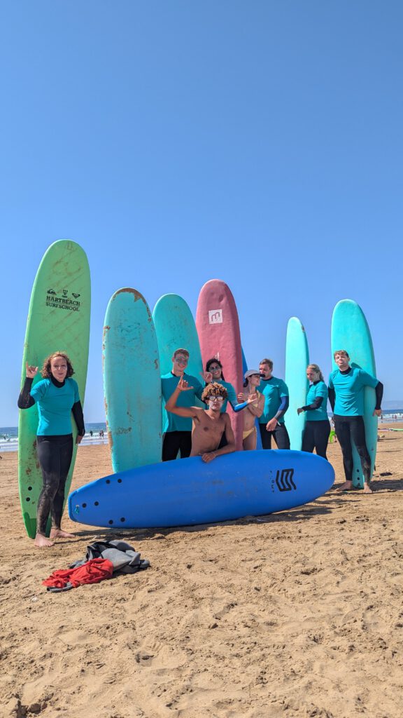 Group of Surfers Having Fun, Young travelers enjoying a surfcamp experience in Tamraght, Morocco—surf lessons, beach bonfires, and new friendships.